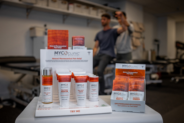 Myco Clinic products are displayed while one man helps another stretch in the background.